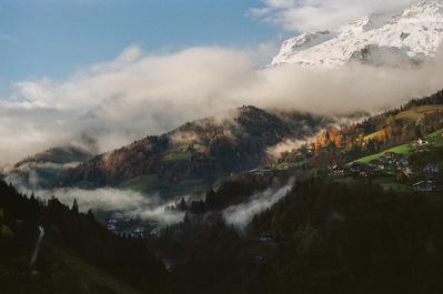 The rising sun draws patches of light on the grassy and coniferous slopes of the mountains, while billows of mist linger in the valleys and a blue sky dominates the snow-capped peaks. France, Auvergne-Rhône-Alpes, Haute-Savoie, Les Clefs, 2021