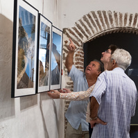 Photographer Olivier Montay discusses with two persons in front of his photos. "Regards croisés : dans les traces de François Arago" exhibition. 2022 September, France, Occitanie, Pyrénées Orientales, Estagel