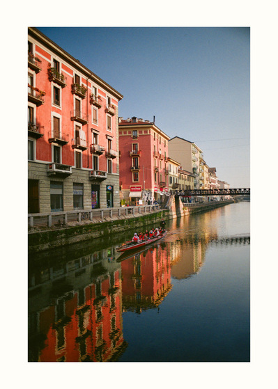 Fine Art print edition of 7 signed & numbered. 50x70 or 30x40 cm on Hahnemühle Bright White paper. Olivier Montay photographer. Pink 4-storey buildings, morning light, canal, rowing boat, calm water, Naviglio Grande di Milano. Film photography