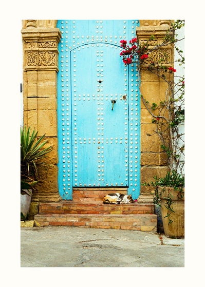 Fine Art print edition of 7 signed & numbered. 50x70 or 30x40 cm on Hahnemühle Bright White paper. Olivier Montay photographer. Sleeping cat, light blue door, ornamented stone columns. Kasbah Udayas. Morocco. Film photography
