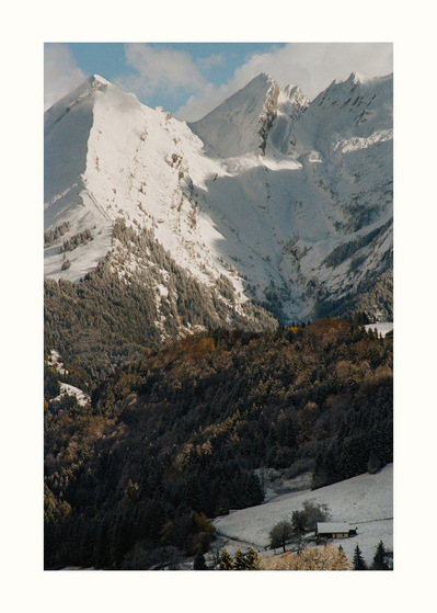 Fine Art print edition of 7 signed & numbered. 50x70 or 30x40 cm on Hahnemühle Bright White paper. Olivier Montay photographer. Snow capped peaks. Autumn hue. Small chalet covered with snow. France, Manigod. Film photography