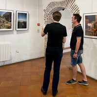 Photographer Olivier Montay discusses with a visitor in front of his photos. "Regards croisés : dans les traces de François Arago" exhibition. 2022 September, France, Occitanie, Pyrénées Orientales, Estagel