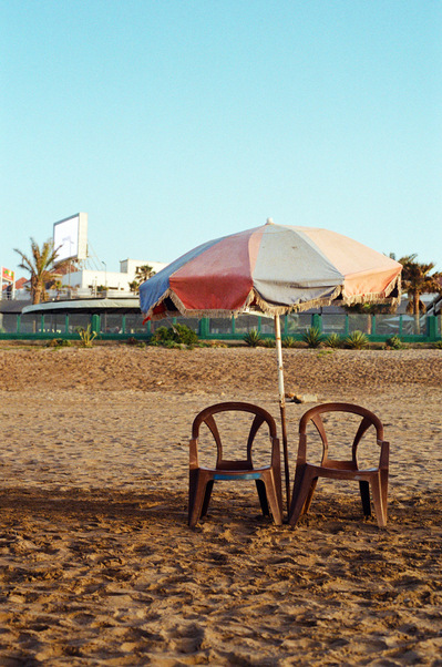 Two lonely brown plastic armchairs under a sun-discolored parasol, on the beach sand. Aïn Diab beach, Casablanca, Morocco, 2020
2 fauteuils de plastique brun sous un parasol décoloré, abandonnés sur une plage de sable. Maroc, 1er mars 2020