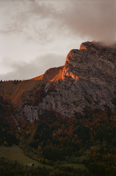 Rocky summit of a mountain lighted in red by sunset. Vegetation slopes, as well as a chalet located in a grassy clearing, are already plunged into darkness. France, Auvergne-Rhône-Alpes, Haute-Savoie, Thônes, 2021
Montagne au soleil couchant