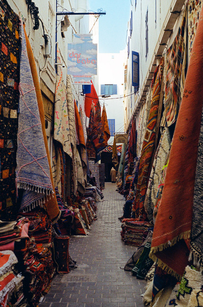 A narrow cobbled street, typical from Essaouira ancient Medina, full of colored carpets for sale. Hoummane Fetouaki Street, Essaouira, Morocco. 2020, March 3rd
Une étroite rue pavée typique de la médina, pleine de tapis colorés. Maroc, 3 mars 2020