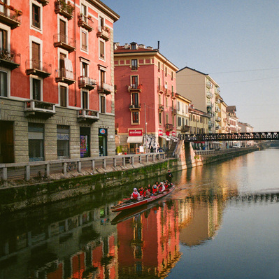 A canal overlooked by pink 4-storey buildings, in the morning light, a thin rowing boat glides on the calm water. Italy, Naviglio Grande di Milano, 2022
Dans le canal bordé d'immeubles roses, un esquif glisse sur l'eau dans la lumière matinale. Milan