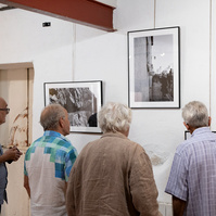 4 visitors to the "Regards Croisés : sur les traces de François Arago" exhibition admire the black & white photos by photographer Corentin Schimel. 2022 September, Espace Mandela, France, Occitanie, Pyrénées Orientales, Estagel.