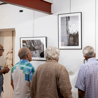 4 visitors to the "Regards Croisés : sur les traces de François Arago" exhibition admire the black & white photos by photographer Corentin Schimel. 2022 September, Espace Mandela, France, Occitanie, Pyrénées Orientales, Estagel.