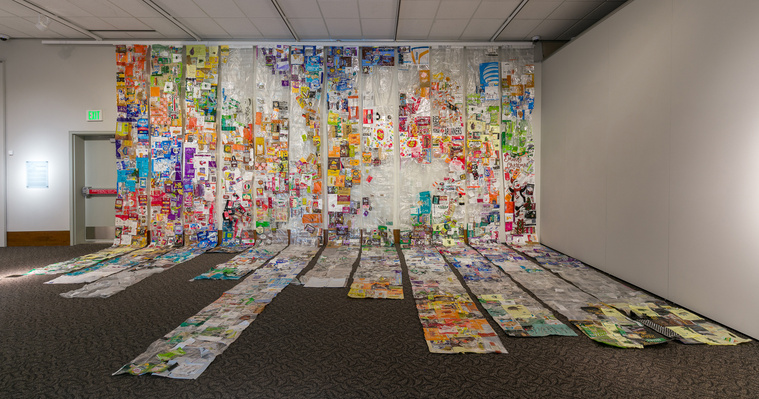 12 banners of sewn single-use plastic cover a gallery wall and spread out onto the floor. Photo by Wes Magyar
