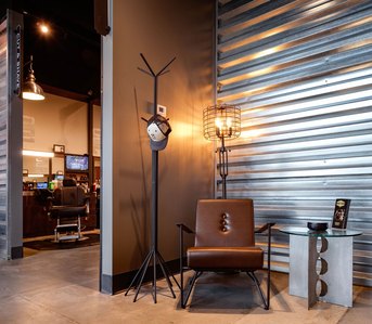 Barber shop waiting area with lounge chair, side table and metal wall treatment.