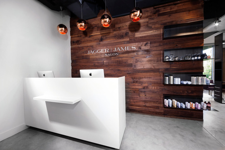 Salon reception area with desk, signage wall and retail shelving