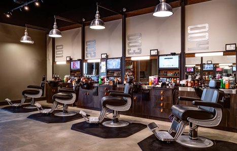 Custom barbering stations with tv, retail shelving, wash bowl and lighting.