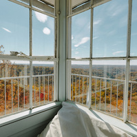 Sunlight filters through old glass windows over a camp bed 