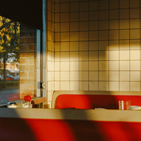 Two red diner benches are lit up with early morning light