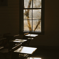 Sunlight streams through an old dusty window lighting up old fashioned school benches