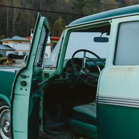 The interior of a vintage car is showing through the open drivers side door covered in morning frost
