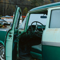 The interior of a vintage car is showing through the open drivers side door covered in morning frost