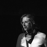 Black and white image of a woman with glasses, light from a window illuminates her face