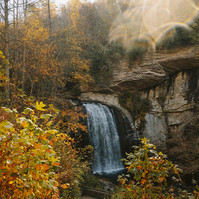 Concrete path leads down to a waterfalll, the scene is framed by Autumn colours