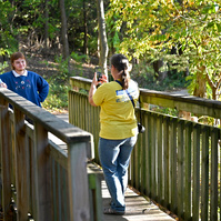 Jay leans against a wooden bridge while Julia Draper takes his senior photos at Cosmo-Bethel Park.