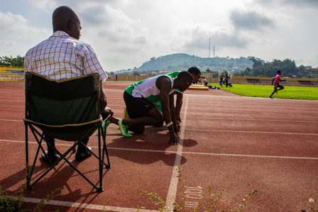 A blind athlete and his guide runner at the starting point on the track, with their coach sitting during a training session.Paralympic Sports Blind Track and Field Athletic
