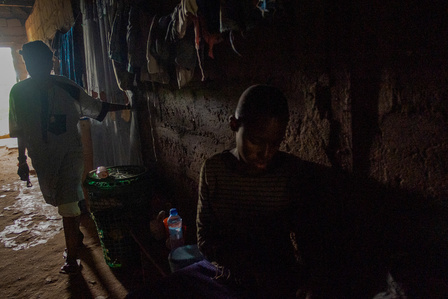Mama Sckadee walking in the dark passage of her building in the refugee camp