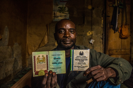 Mustapha, a Sierra Leonean refugee holds his identity cards