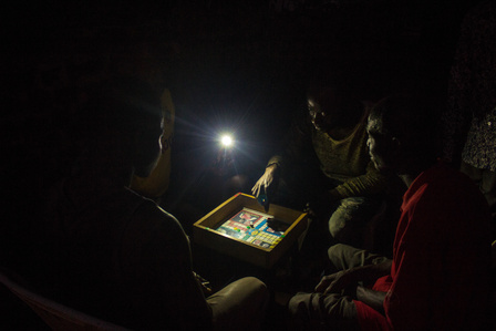 Adults playing the Ludo game at night at the Oru International Refugee Camp, Nigeria. Liberia Sierra Leone Civil War Refugee