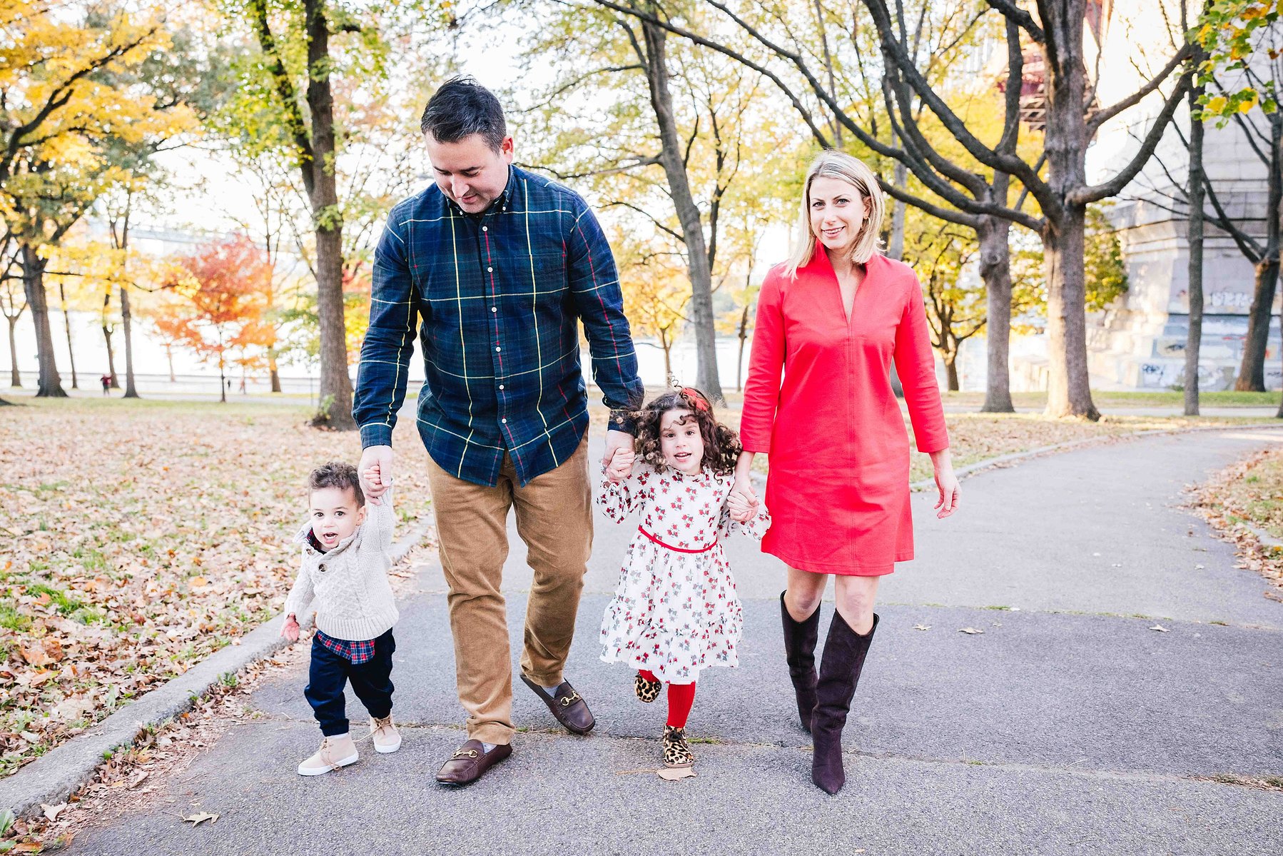 family of 4 walking hand in hand, amongst the fall leaves in astoria park. mc3 photo family portrait sessions, nyc based photographer 
