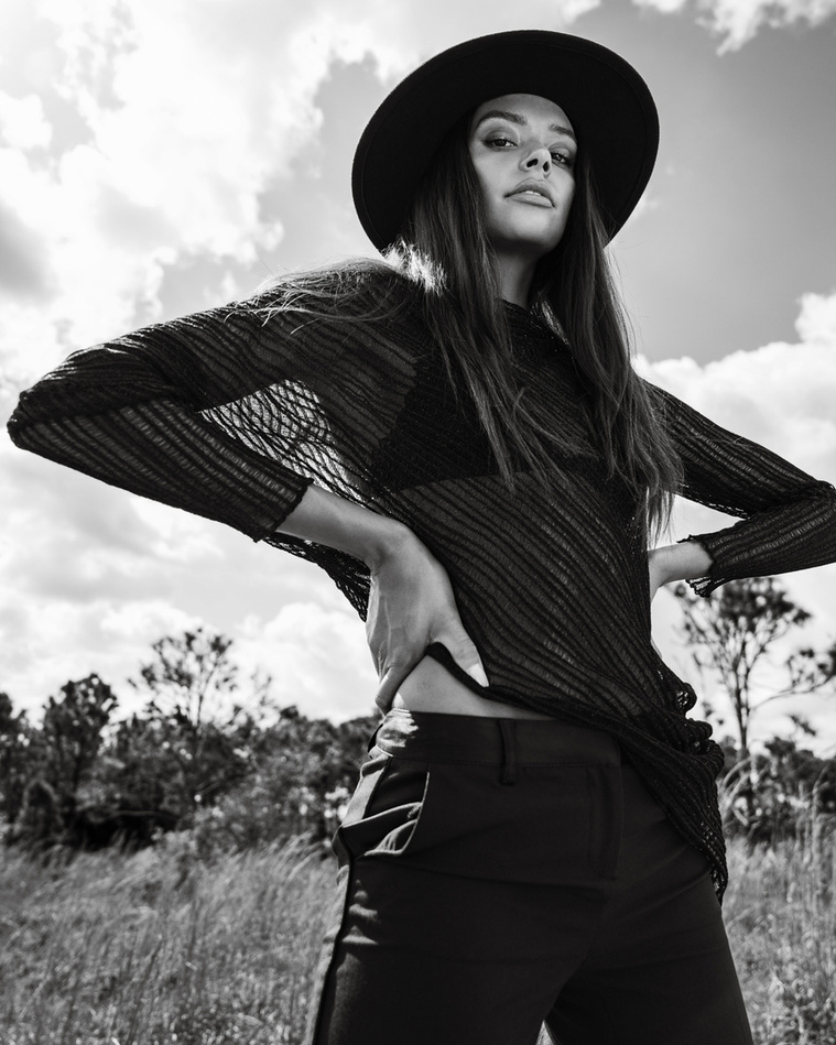 Model Dominique Millette from Caroline Gleason Management in Miami wearing a black hat and black clothing in the middle of a prairie by Miami fashion photographer Alejandro Rivera