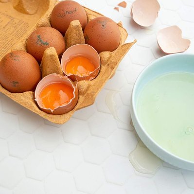 brown eggs in egg carton two broken with yolk in shell bowl with egg whites