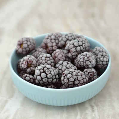 frozen blackberries in a bowl on marble slab