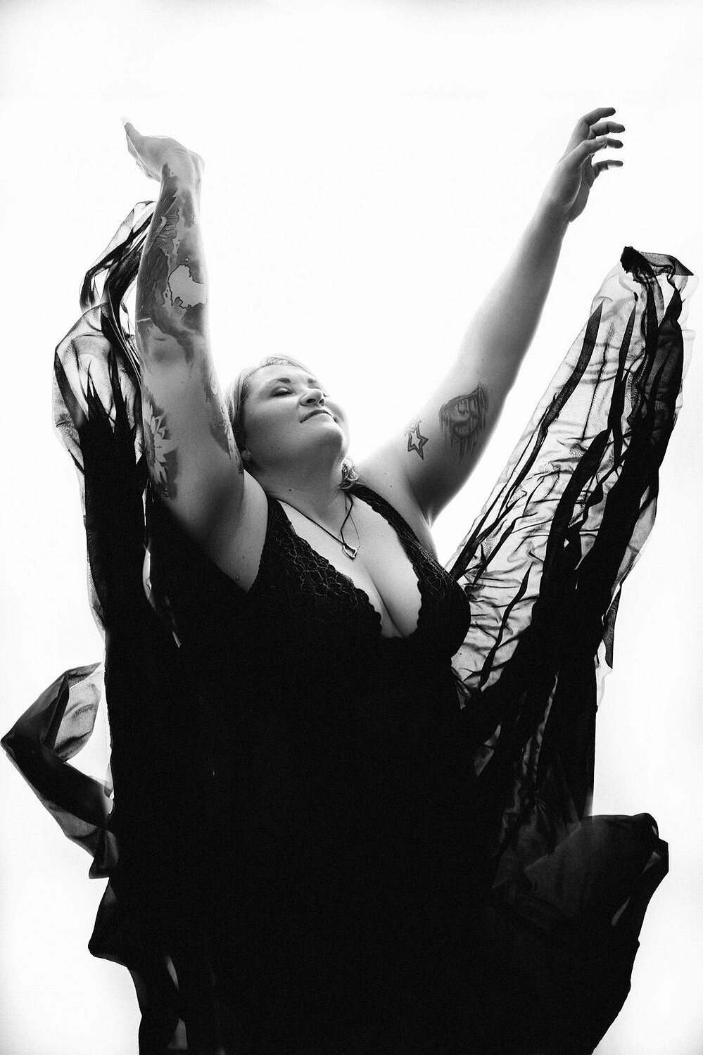 A curvy blonde woman with tattoos throws her skirts upwards, they look like water