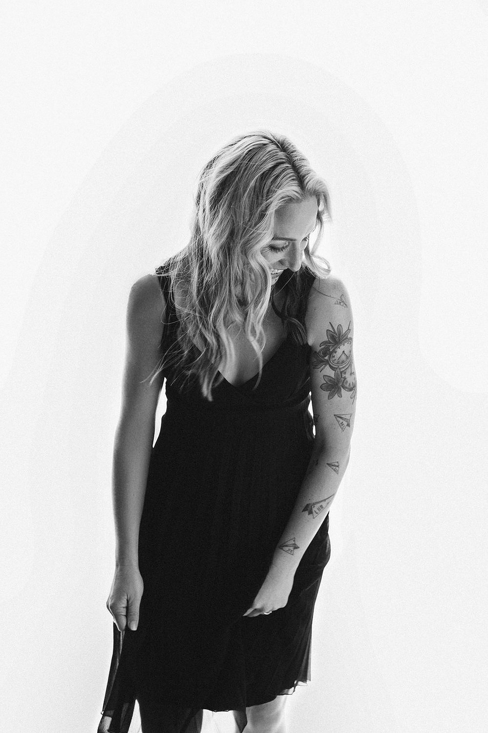 A quirky woman with long blonde hair laughs self consciously 