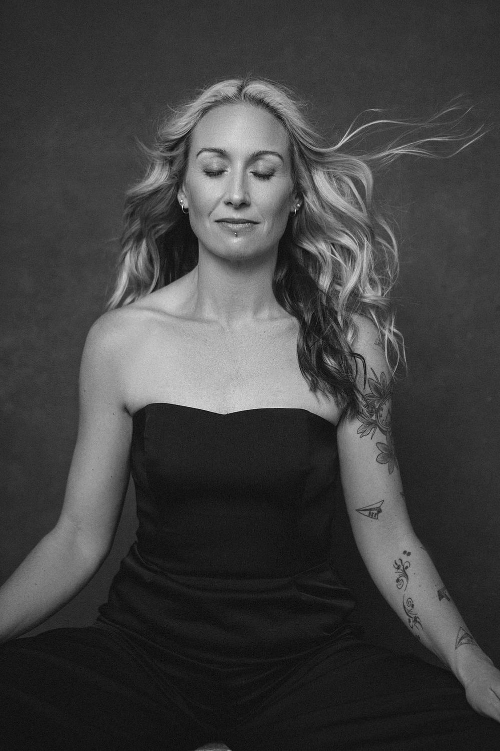 A quirky woman with long blonde hair blowing in the wind, she sits and meditates