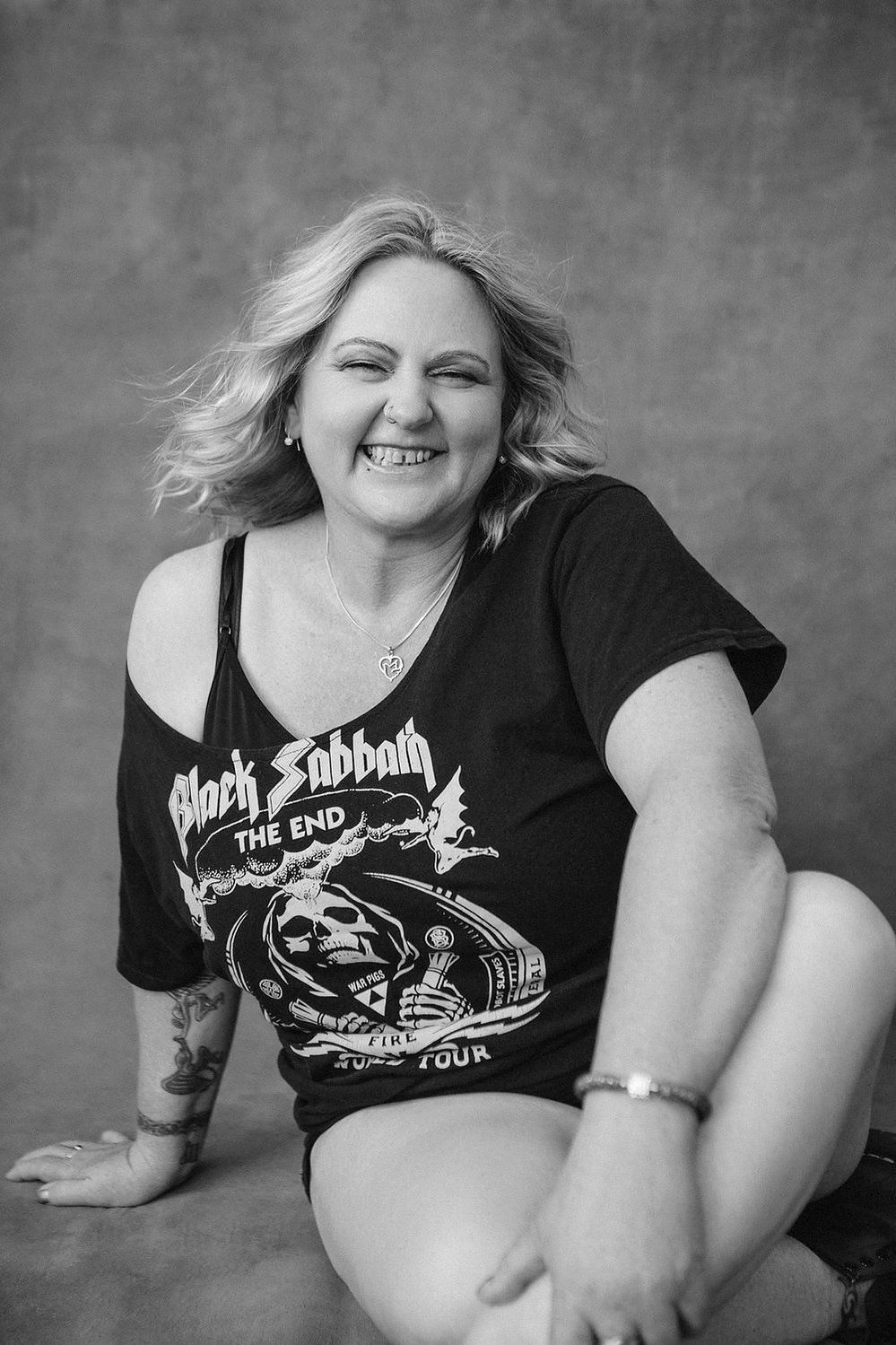 A curvaceous woman with a blonde bob poses in a funky band tee