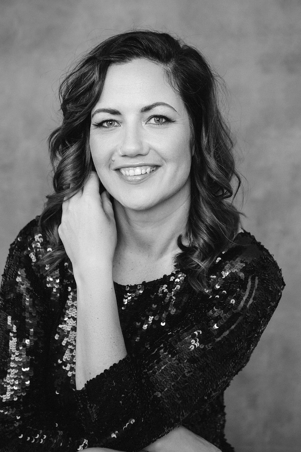 A glamourous young brunette woman poses in a sequinned dress
