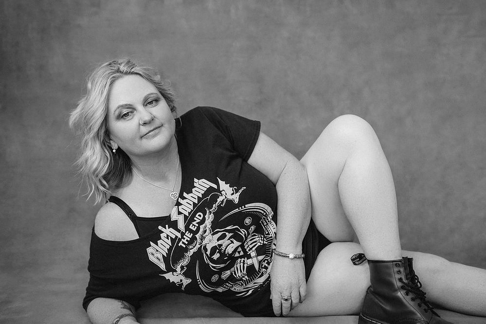 A curvaceous woman with a blonde bob poses wearing a funky band t-shirt and doc martens