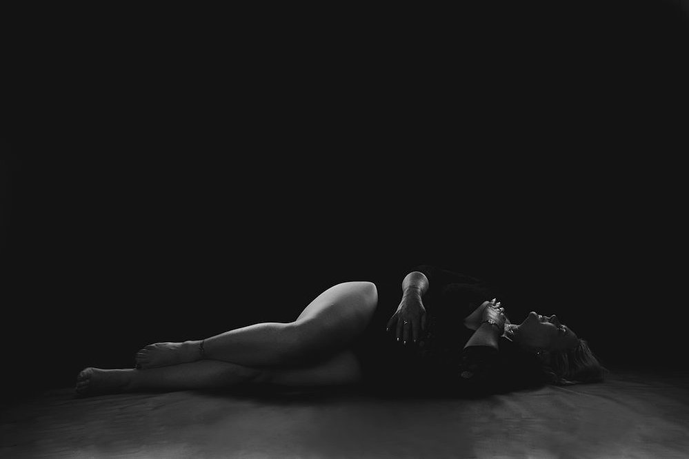 A curvaceous woman with a blonde bob poses in a boudoir style