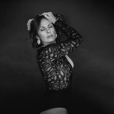 A brunette woman poses in a boudoir style with her eyes closed