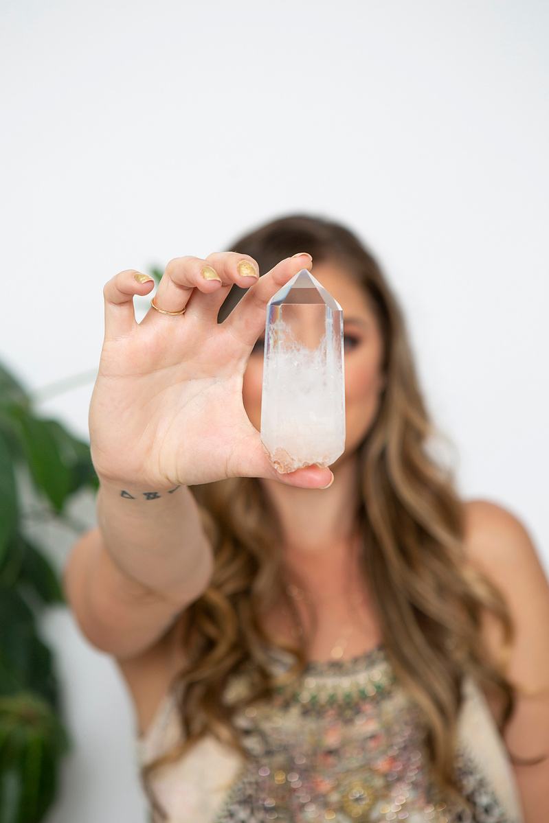 A young woman holds a crystal to the camera, obscuring her face