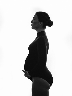 Young pregnant brunette woman mostly silhouetted against a white background