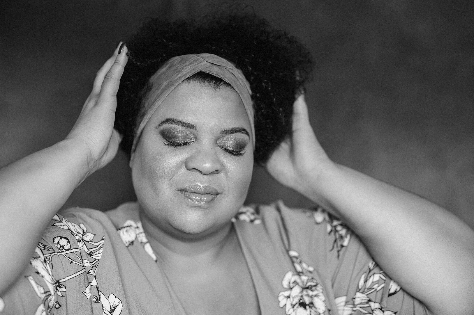 A curvaceous woman caress her afro, her eyes are closed in contemplation