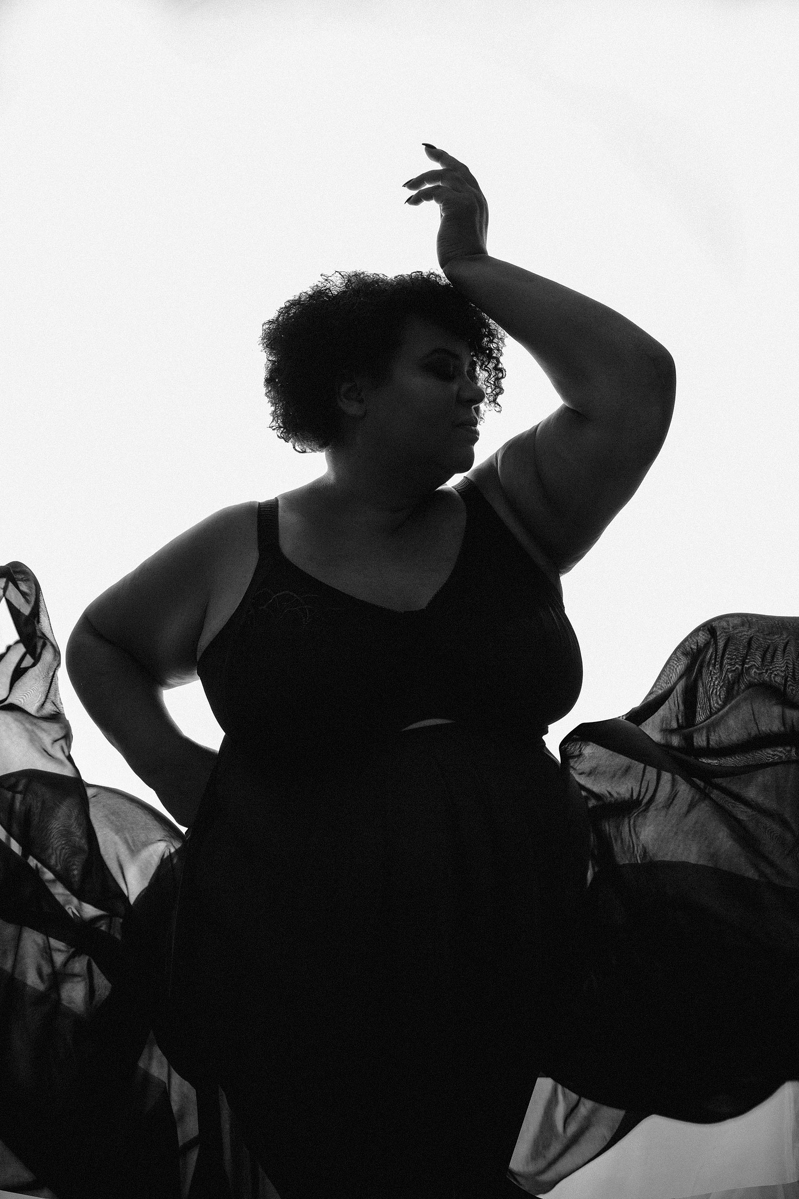 A woman is silhouetted, she has thrown her skirts up around her