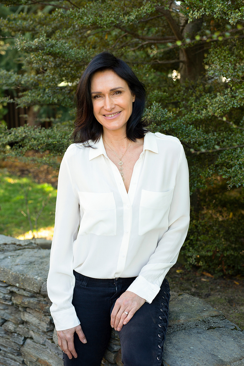 A professional brunette wearing a white shirt smiles into the camera