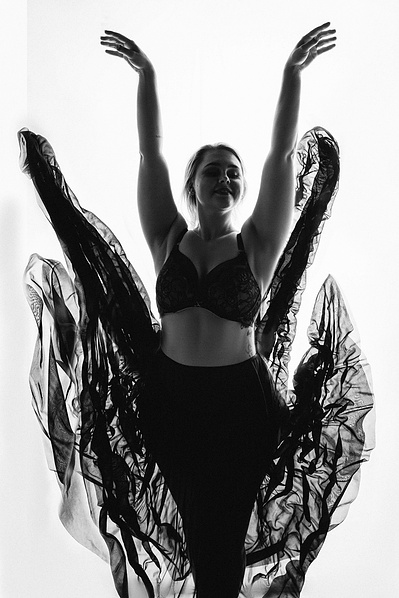 A woman throws her skirts in the air, she is silhouetted 