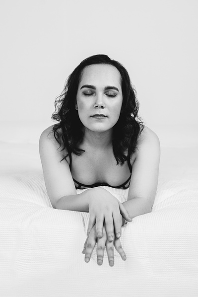 A woman leans forward, one hand on the other with her eyes closed