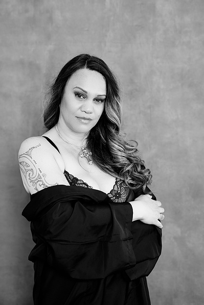 Striking woman gives sultry look to the camera, she has a jacket draped around her torso
