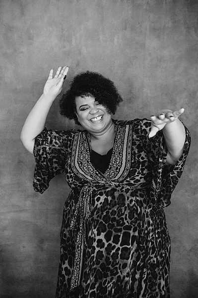 A curvaceous black woman dances with her hands in the air