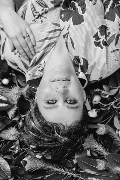 A woman with short brown hair lays on a bed of leaves